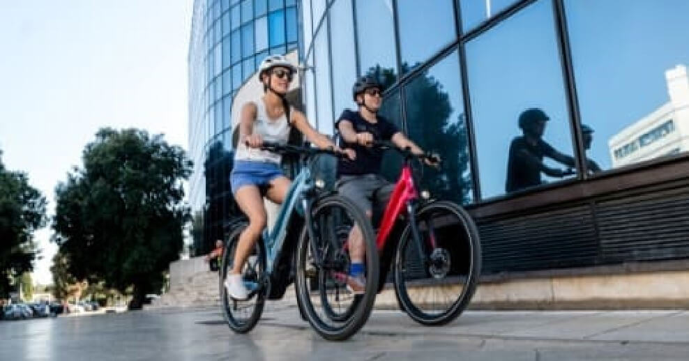 People cycling besides a building